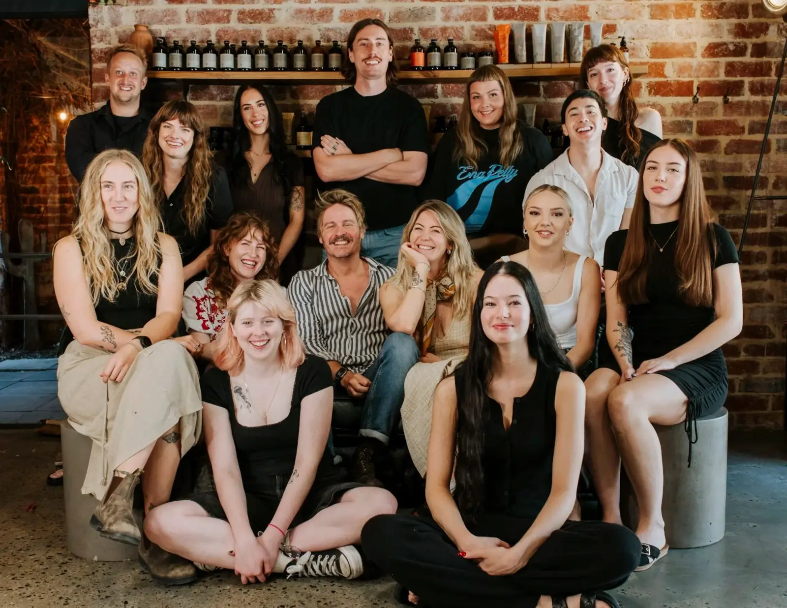 The George & Ivy team of fifteen stylists, colourists and apprentices gathered together in the Fremantle salon, in front of the exposed brick wall and the timber shelf of Oway products